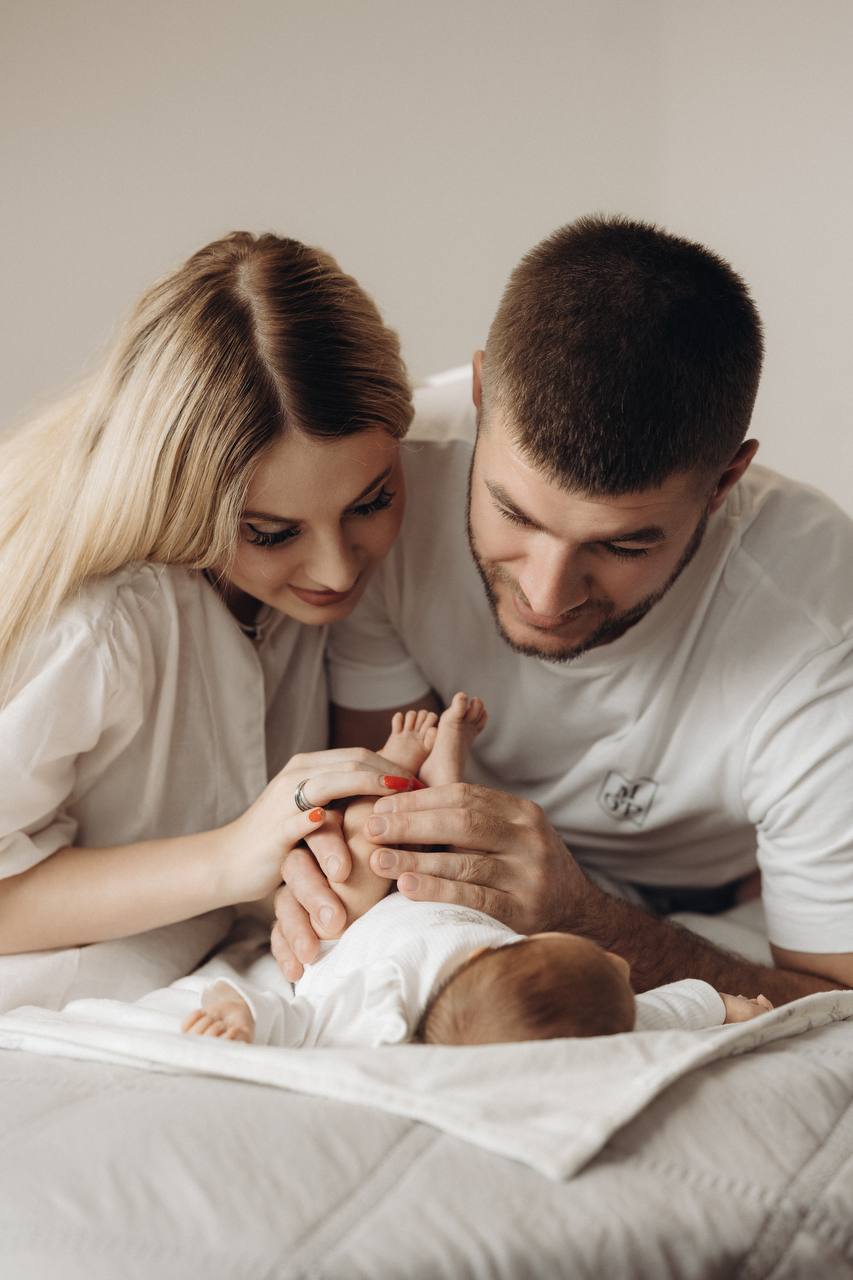 New parents leaning over their newborn