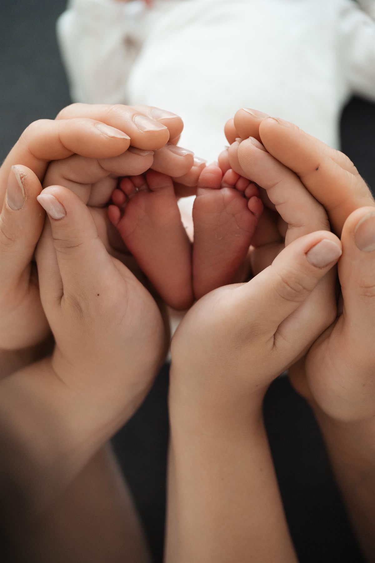 A newborn's feet cradled in both parents' hands