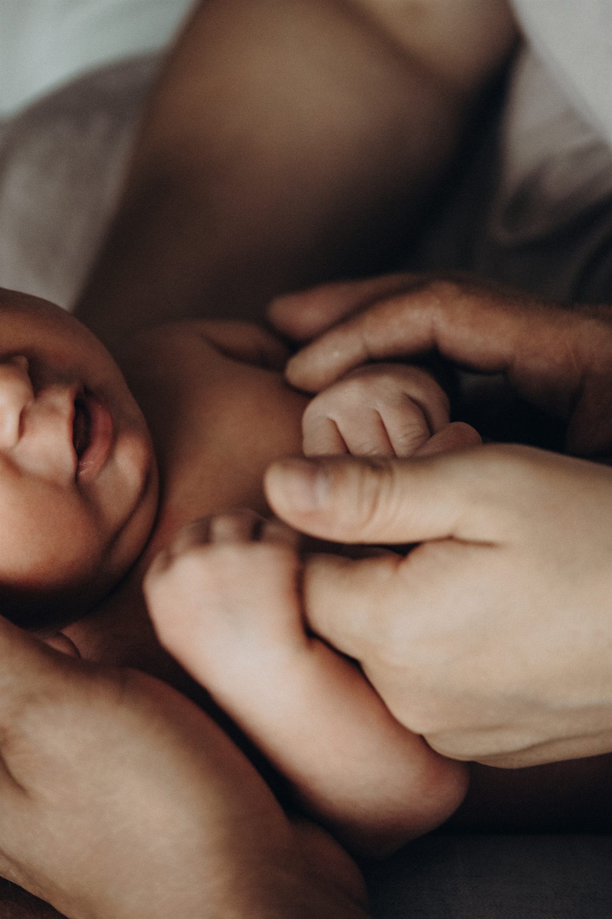A newborn yawning while holding a parent's finger