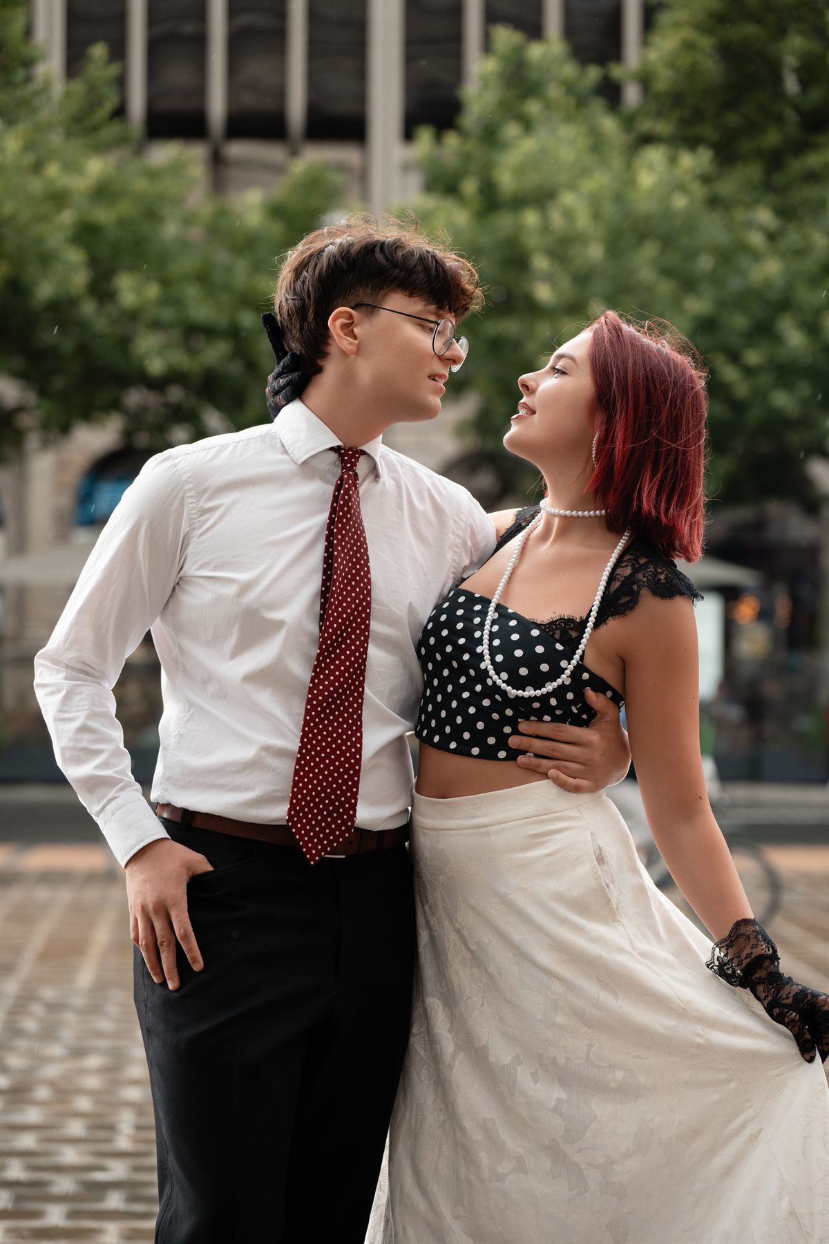 A young couple in retro outfits laughing together on a city square