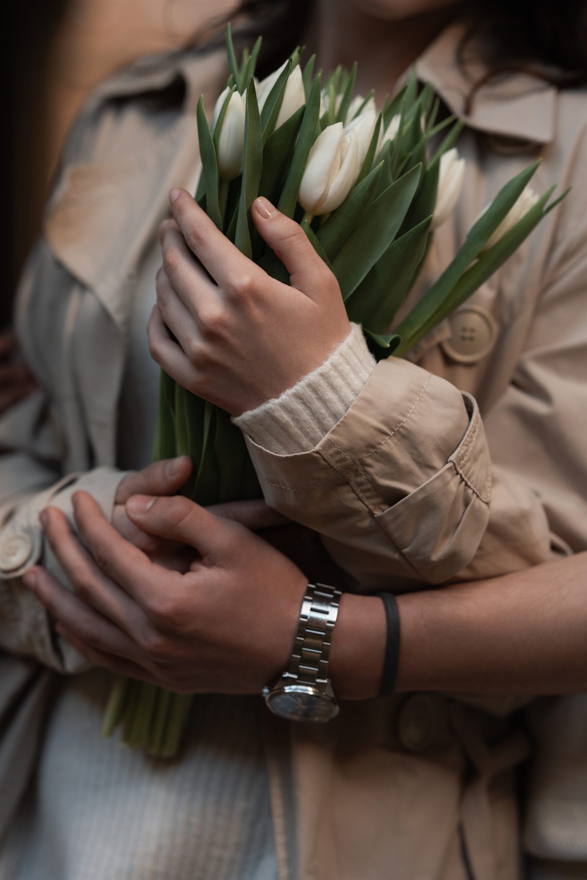 A couple holding a bouquet of white tulips together