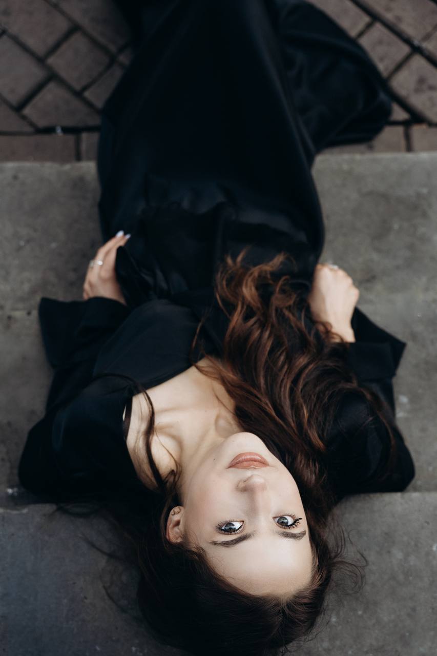 A woman in black lying on stone steps, photographed from above