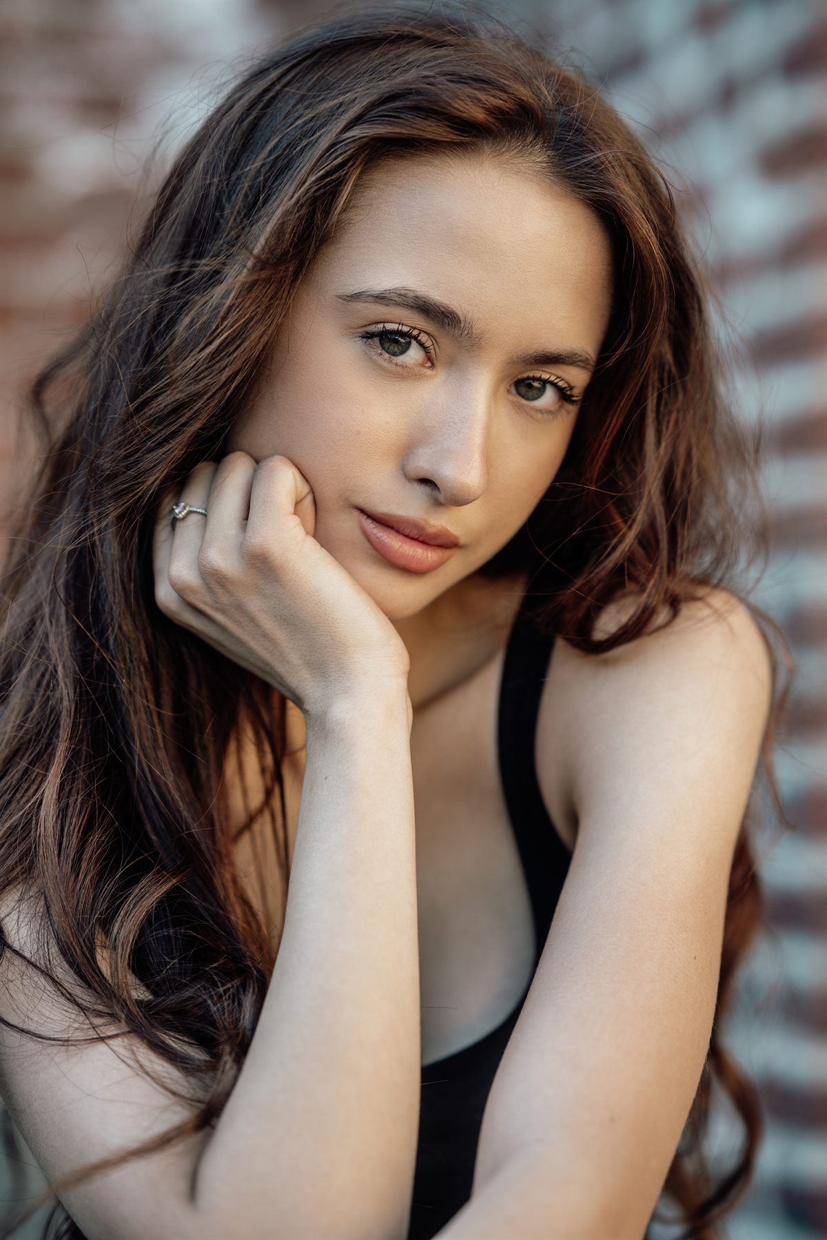 Close-up portrait of a woman by a brick wall