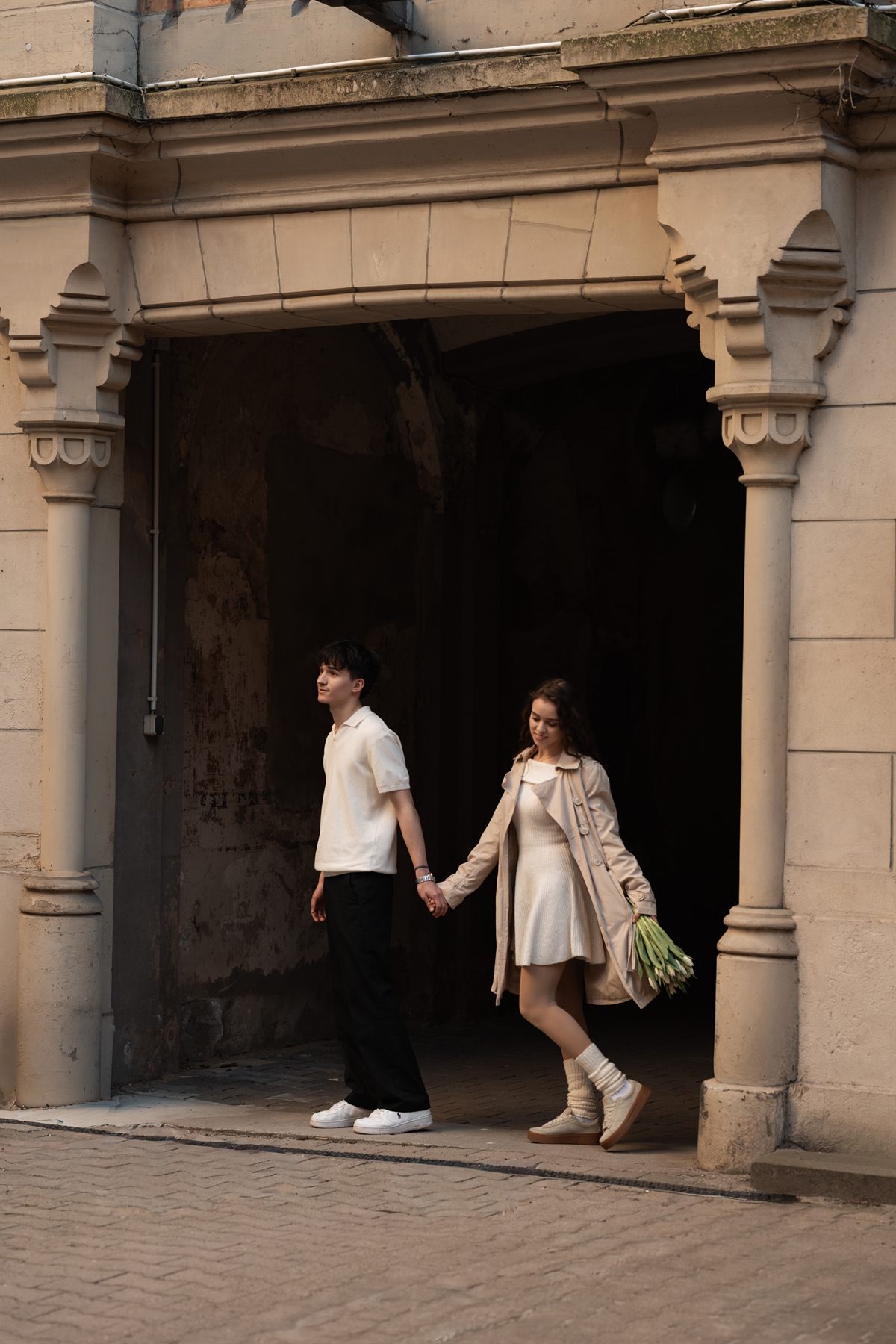 A couple walking out of a stone archway