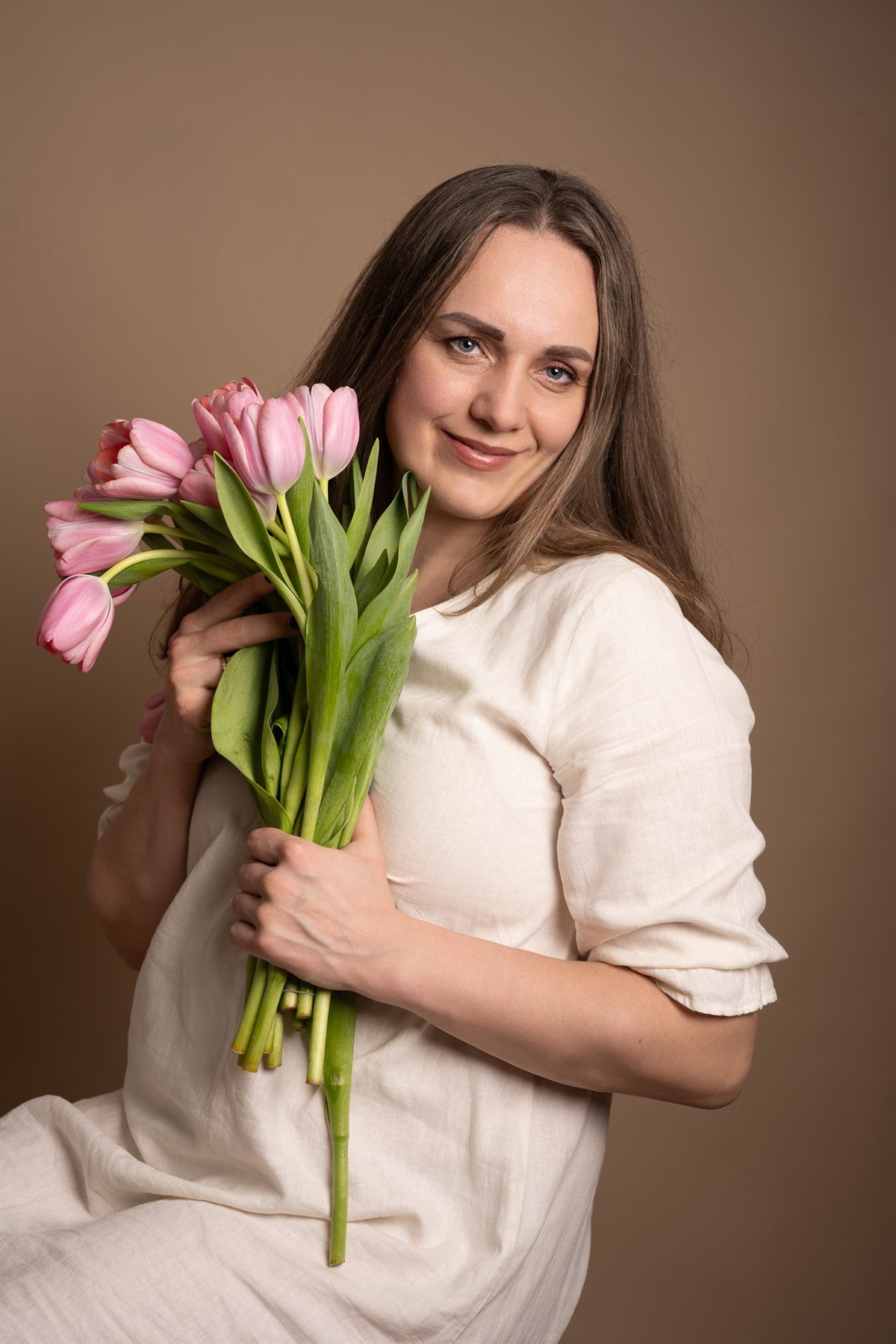 Yuliya in a linen dress holding pink tulips